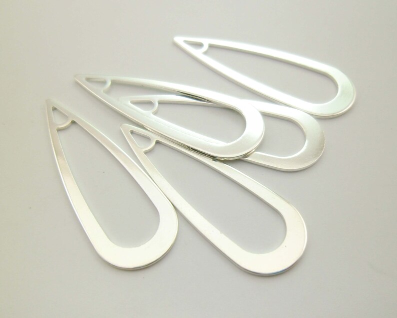 May include: Five silver-toned metal teardrop-shaped earring blanks with a hole at the top.