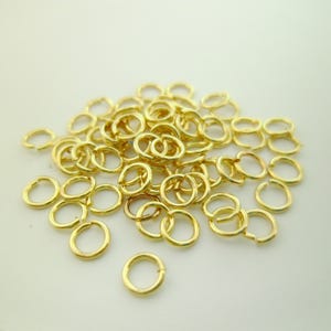 Könnte beinhalten: Ein Haufen goldener Sprungringe, eine Art von Schmuckzubehör, das zum Verbinden von Ketten, Schnüren und anderen Schmuckkomponenten verwendet wird.