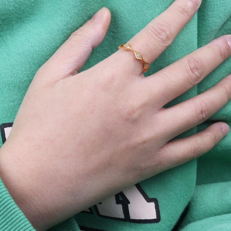 Puede incluir: Un anillo de oro con peque&ntilde;as piedras transparentes engastadas en una banda ondulada.