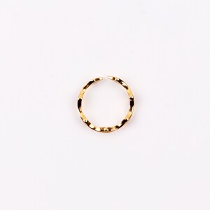 Puede incluir: Un anillo dorado con una banda ondulada y texturizada.