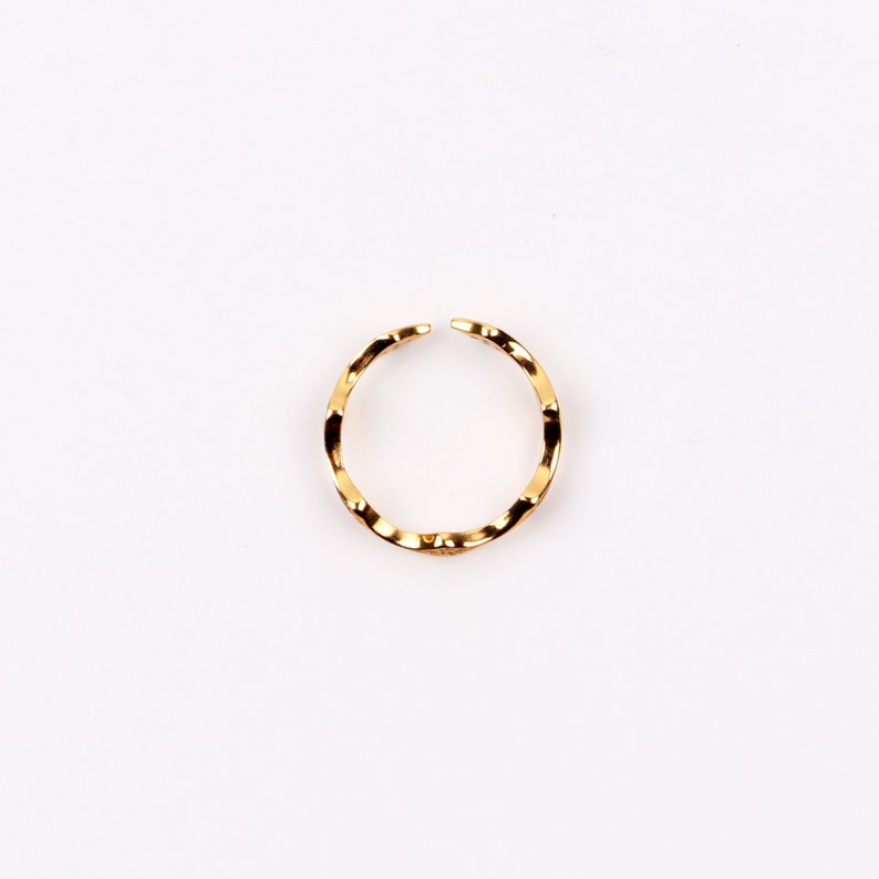 Puede incluir: Un anillo dorado con una banda ondulada y texturizada.