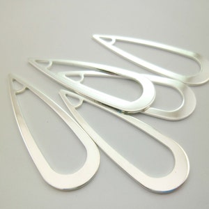 May include: Five silver metal teardrop-shaped earring blanks with a rounded edge and a hole at the top.