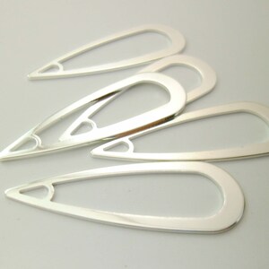 May include: Five silver metal teardrop-shaped jewelry findings with a heart-shaped cutout at the top.
