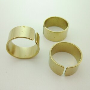 May include: Three gold-toned metal rings with a slightly open design. The rings are smooth and have a subtle sheen.