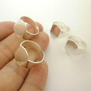 Puede incluir: Tres anillos ajustables de plata con parte superior hexagonal. Los anillos se muestran en una mano.