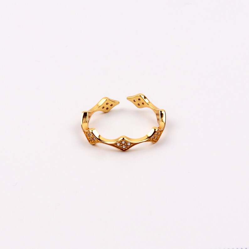 Puede incluir: Un anillo de oro con un dise&ntilde;o geom&eacute;trico y peque&ntilde;as piedras transparentes.