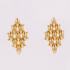May include: A pair of gold dangle earrings with a geometric design. The earrings are made of multiple oval-shaped beads.