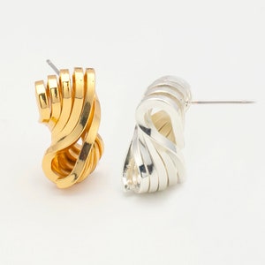 May include: A pair of earrings, one gold and one silver, with a unique, twisted, wave-like design.