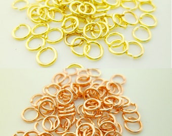 May include: A pile of gold jump rings and a pile of rose gold jump rings. The jump rings are small and round.