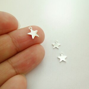 May include: Three silver star-shaped charms with a loop at the top. The charms are small and delicate, perfect for adding a touch of sparkle to jewelry or crafts.