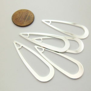 May include: Five silver-toned metal teardrop-shaped earring blanks with a hole at the top. The blanks are approximately the size of a US penny.