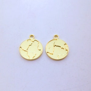 Puede incluir: Dos abalorios de metal de color dorado con forma de Tierra. Cada abalorio tiene un diseño en relieve texturizado de los continentes.