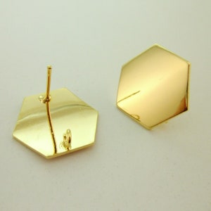 May include: A pair of gold-toned hexagonal stud earrings. The earrings have a post and a small loop on the back.