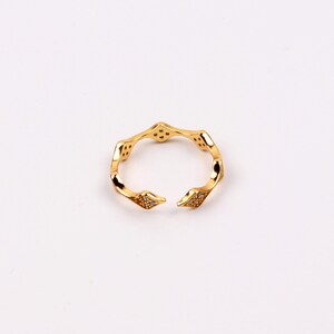 Puede incluir: Un anillo de oro con un dise&ntilde;o geom&eacute;trico adornado con peque&ntilde;as piedras transparentes.
