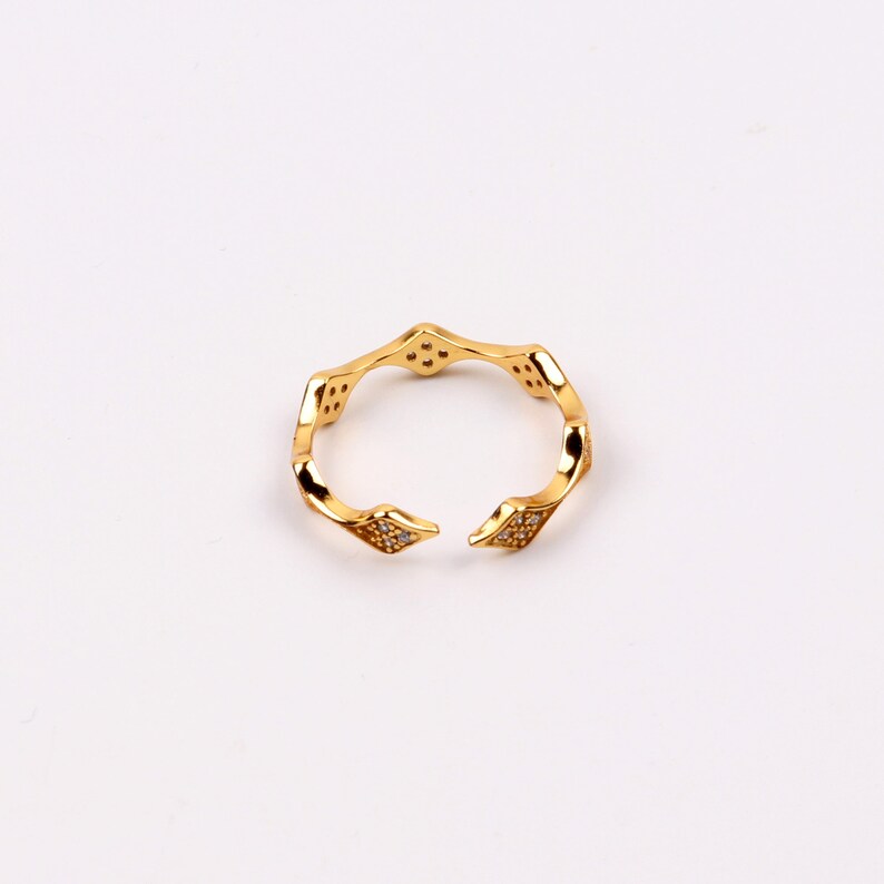 Puede incluir: Un anillo de oro con un dise&ntilde;o geom&eacute;trico adornado con peque&ntilde;as piedras transparentes.