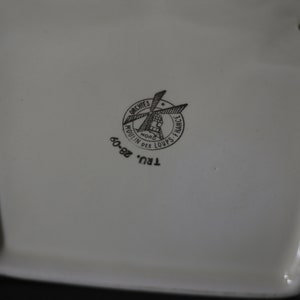 May include: Cream-colored ceramic piece with a black logo that reads "ORCHIES NORD MOULIN DES LOUPS FRANCE" and the numbers "60-82". The logo features a windmill design. The piece has a rectangular shape.
