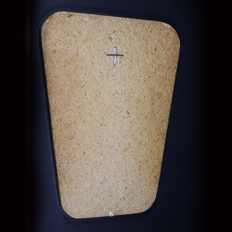 May include: A close-up of a light brown, rectangular, wooden mirror with a black frame. The mirror has a small, silver cross in the center.