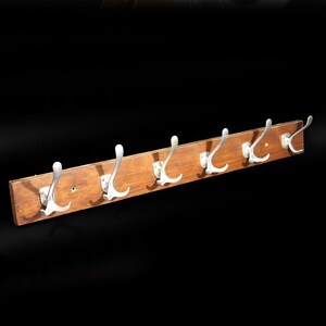 Peut inclure: Un porte-manteau rectangulaire en bois doté de six crochets en métal argenté montés sur une rangée horizontale. Le bois présente une finition brun moyen avec un grain visible, et chaque crochet est fixé par une plaque de base rectangulaire.