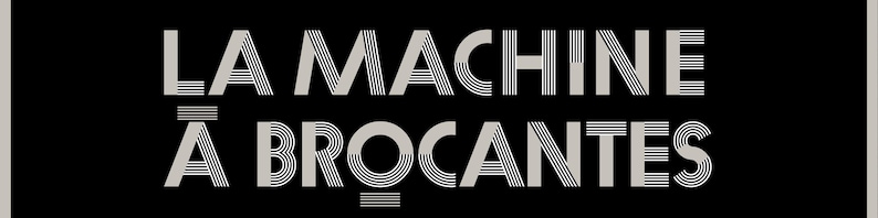 May include: A black rectangular sign with the text "LA MACHINE &Agrave; BROCANTES" in a stylized, art deco font. The text is in light gray, with the words stacked vertically.