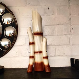 Peut inclure: Un vase en céramique en forme de bambou, de couleur crème et marron. Le vase présente une texture côtelée et des bandes marron, imitant l'apparence des tiges de bambou. Un élément décoratif pour une ambiance naturelle.