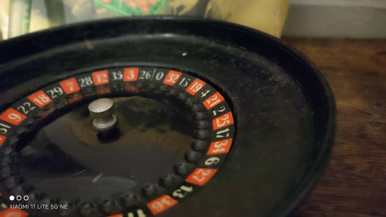 May include: A black roulette wheel featuring a central silver knob and a circular track with alternating red and black numbered segments. The numbers 9, 22, 18, 29, 7, 28, 12, 35, 3, 26, 0, 32, 15, 19, 4, 21, 25, 17, 34, 6, 27, 13, 36 are visible.