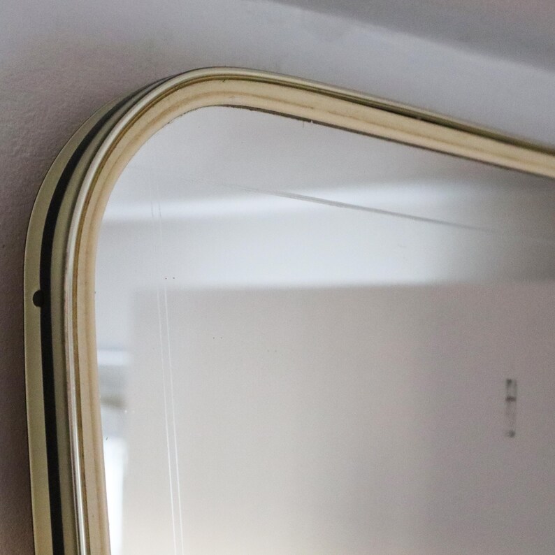 May include: Close-up of the top edge of a large, rectangular mirror with a thick, rounded, gold-colored frame.