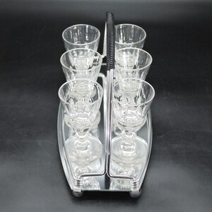May include: A vintage silver-toned serving tray with a handle, holding six clear crystal stemmed glasses. The glasses have a decorative pattern and are arranged in two rows of three. The handle is black and ribbed.