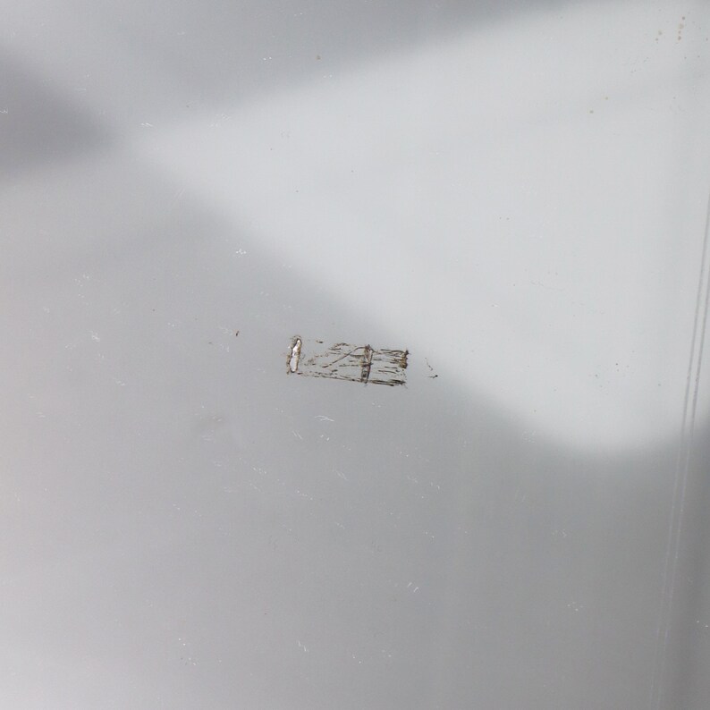 May include: A close-up of a light gray surface with a small, thin, silver scratch.