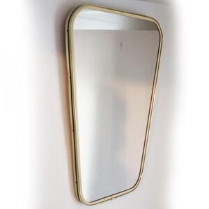 May include: A large, gold-framed mirror with a slightly curved, rectangular shape. The mirror is hanging on a white wall.
