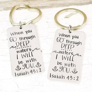 May include: Two silver keychains with heart and circle rings. Each keychain has a rectangular tag with the text "When you go through deep waters, I will be with you. Isaiah 43:2" and an anchor symbol.