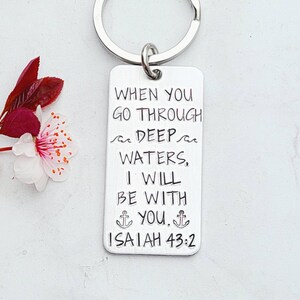 May include: Silver keychain with the text "WHEN YOU GO THROUGH DEEP WATERS, I WILL BE WITH YOU. ISAIAH 43:2" and two anchor symbols.