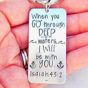 May include: Silver keychain with the text "When you GO through DEEP waters, I Will be with YOU. Isaiah 43:2" and two anchor symbols.