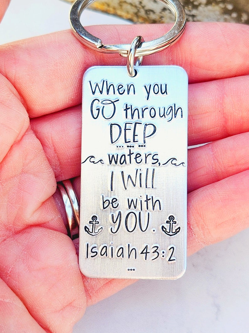 May include: Silver keychain with the text "When you GO through DEEP waters, I Will be with YOU. Isaiah 43:2" and two anchor symbols.