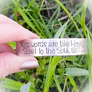 May include: A silver bracelet with the inscription "Kind words are like honey, Sweet to the soul" and a small bee design.