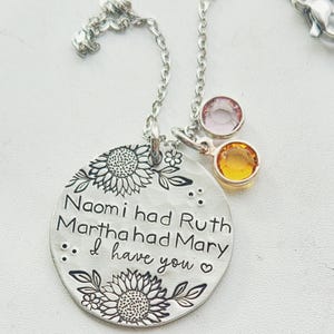 Może przedstawiać: Srebrny naszyjnik z wisiorkiem z okrągłym urokiem z wygrawerowanym tekstem i kwiatowymi wzorami. Tekst brzmi "Naomi had Ruth Martha had Mary... I have you." Dwa urocze kamienie szlachetne, jeden r&oacute;żowy i jeden ż&oacute;łty, zwisają z łańcuszka.