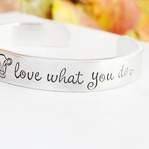 Puede incluir: Pulsera de plata con la inscripción "You love what you do" y una pequeña ilustración de una vaca.