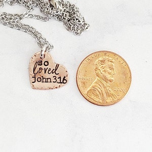 May include: A silver chain necklace with a copper heart pendant that says "so loved John 3:16".
