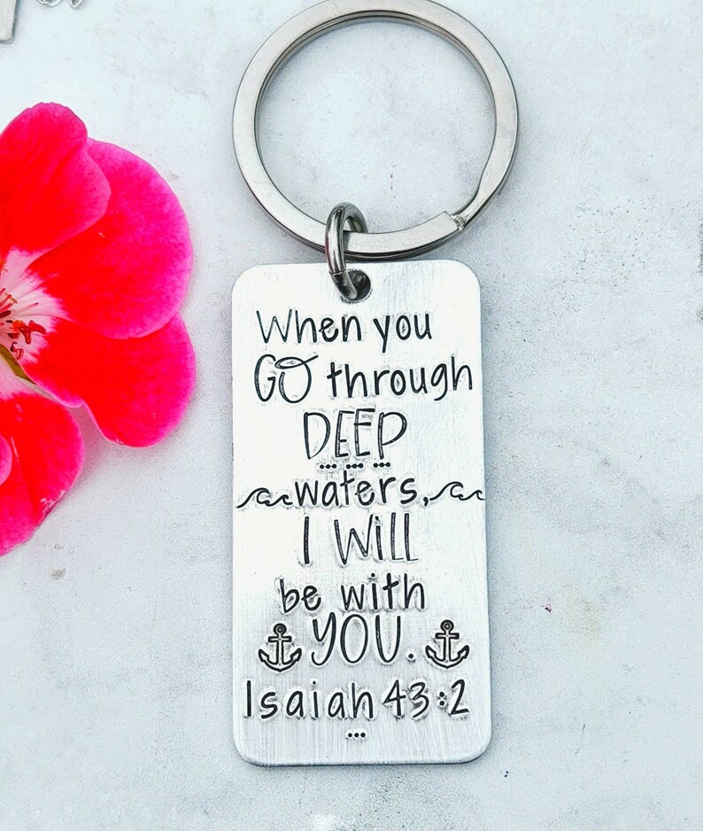 May include: Silver keychain with a rectangular tag that reads "When you go through DEEP waters, I WILL be with YOU. Isaiah 43:2". The tag has a wavy line above and below the word "waters" and two anchor symbols on either side of the word "YOU".
