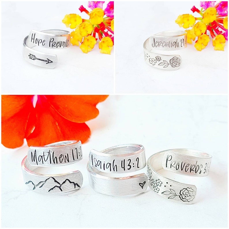 Puede incluir: Una colecci&oacute;n de cinco anillos envolventes de tono plateado con textos y s&iacute;mbolos grabados. Los anillos muestran frases como Hope Prevails, Jeremiah 29, Matthew 17, Isaiah 43:2 y Proverbs 31, acompa&ntilde;adas de dise&ntilde;os grabados de flechas, flores, monta&ntilde;as y un coraz&oacute;n.