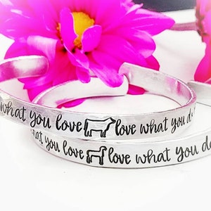 May include: Two silver bracelets with the inscription "Do what you love love what you do" on one bracelet and "What you love love what you do" on the other bracelet.