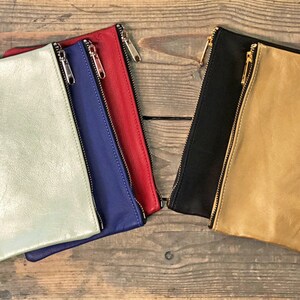 May include: Five leather zipper pouches in different colors: light green, blue, red, black, and tan.