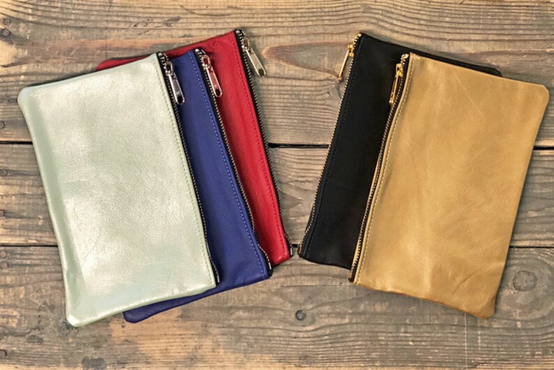 May include: Five leather zipper pouches in different colors: light green, blue, red, black, and tan.