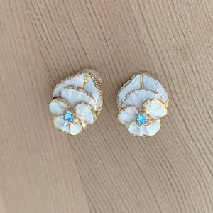Wit emaille en goud getinte florale clip-on oorbellen met blauwe strass steentjes