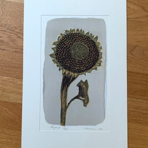 May include: A black and gold print of a sunflower with the text "Serigraph 4/25" and "Ohman '67" in the bottom corners.