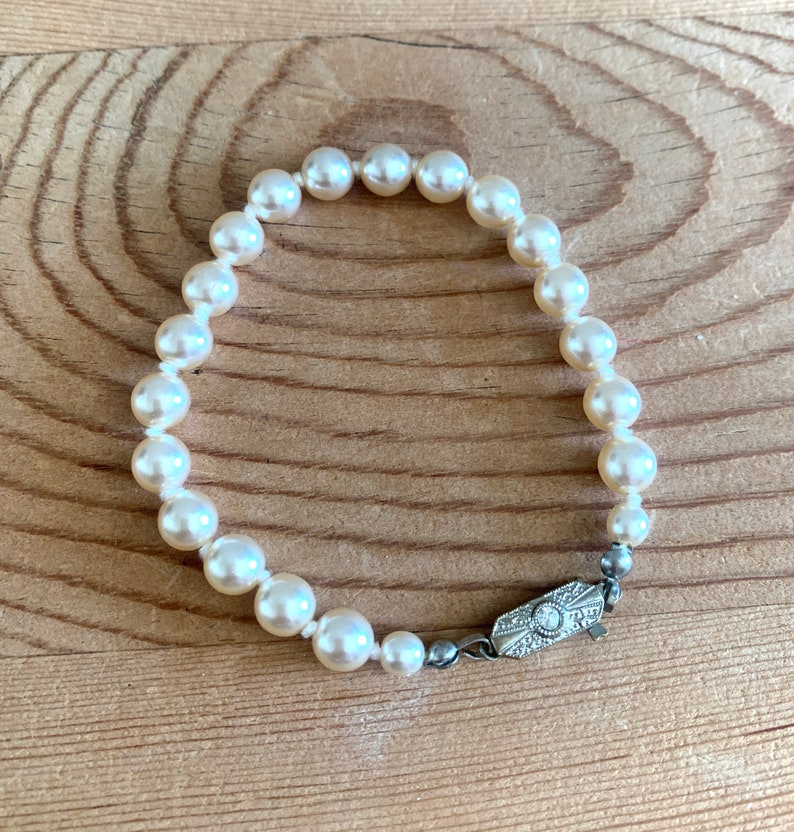 May include: A white pearl bracelet with a silver clasp. The clasp has a small diamond in the center.
