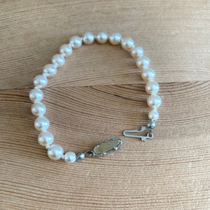 May include: A white pearl bracelet with a silver clasp. The bracelet is made of small, round pearls and has a simple design.