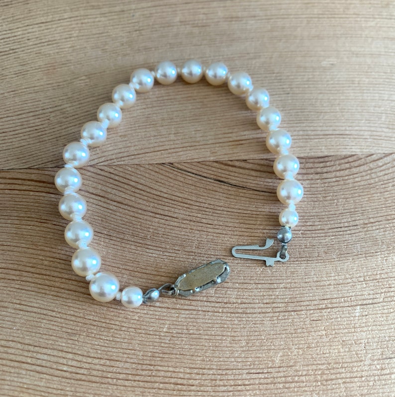 May include: A white pearl bracelet with a silver clasp. The bracelet is made of small, round pearls and has a simple design.