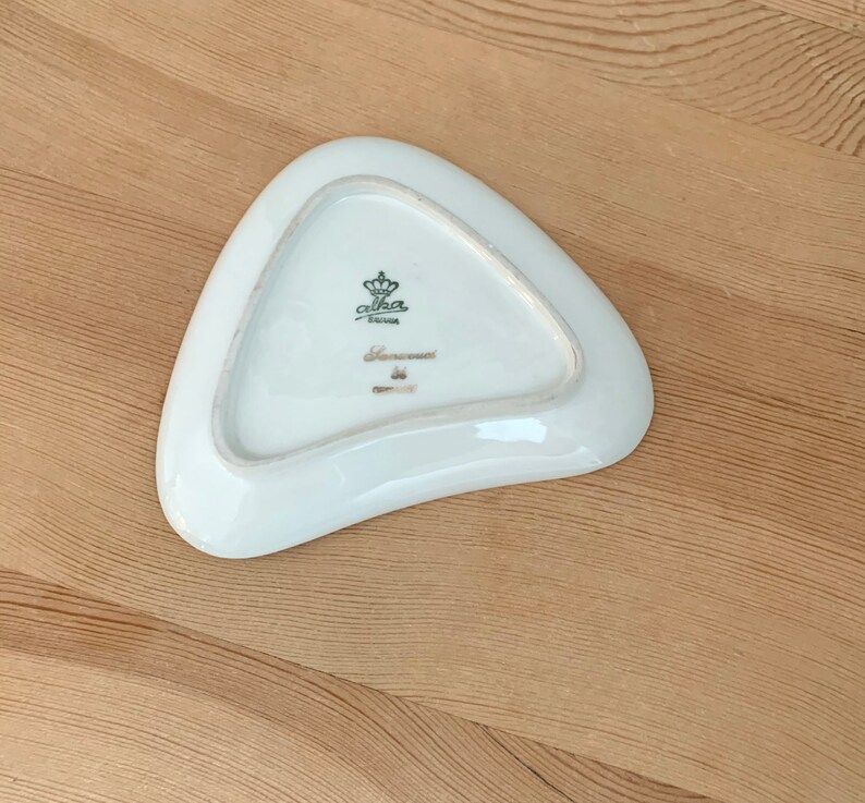 May include: A white triangular ceramic dish with a gold crown and the text "Carlha Bavaria" on the bottom.