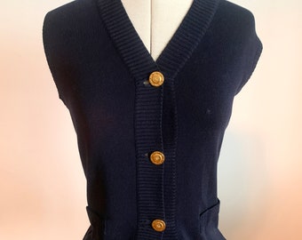 May include: A navy blue sleeveless cardigan with a v-neck and gold buttons.
