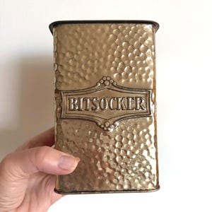 Op de afbeelding: Een witte keramische mok met een zwart handvat en de tekst "But First, Coffee" in een handschriftstijl. De mok staat op een wit oppervlak. De mok is ongeveer 10 cm hoog.